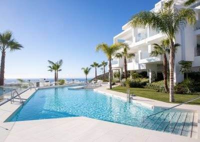 Palo Alto luxury development communal pool with palm trees, white modern apartments, and Mediterranean sea views